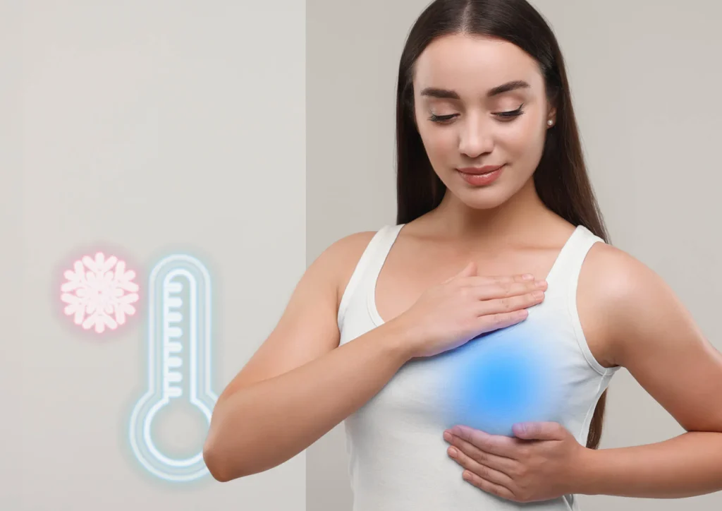 Kobieta w białej koszulce przykładająca dłonie do piersi z niebieskim podświetleniem oraz ikoną płatka śniegu i termometru w tle.
