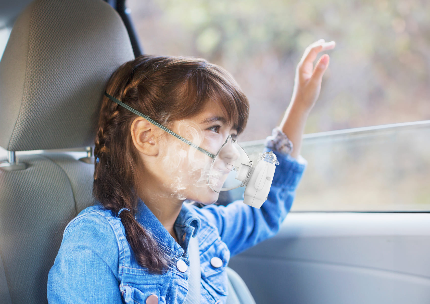 Dziewczynka w samochodzie używa przenośnego nebulizatora Neno Atemo.
