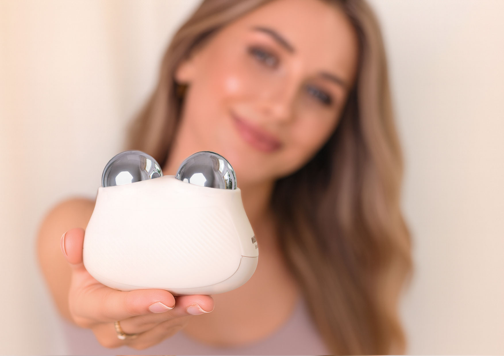 Kobieta prezentuje masażer Neno Naya z podwójną, ergonomiczną głowicą masującą dopasowaną do konturów twarzy.