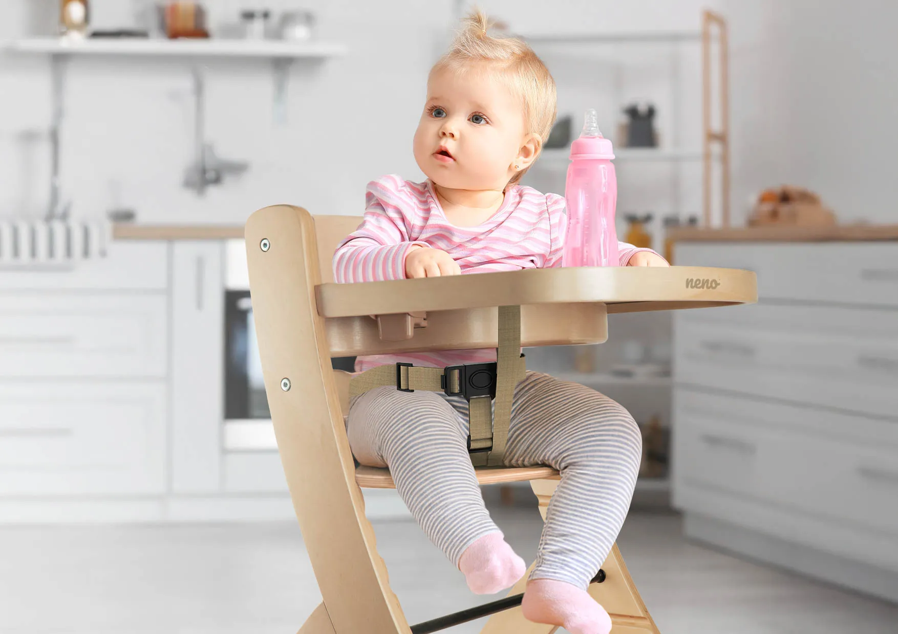 Małe dziecko siedzi w krzesełku Neno Pino w kuchni. Ilustracja podkreśla wygodę i dopasowanie mebla do rozwoju dziecka.