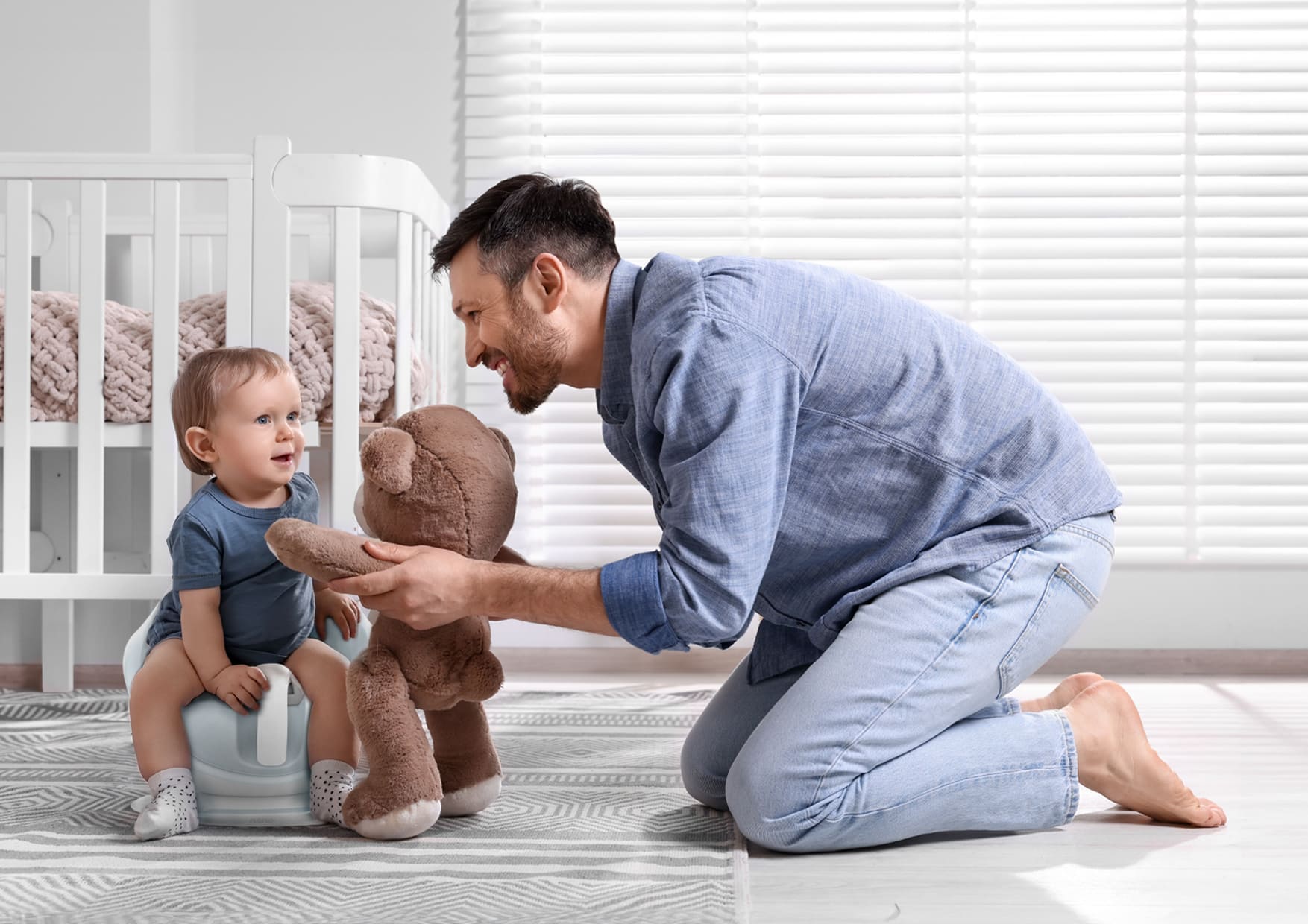 Baby on potty playing with teddy bear with daddy