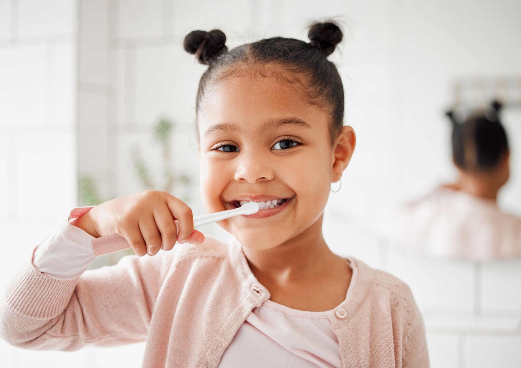 Małe dziecko trzymające elektryczną szczoteczkę do zębów w łazience