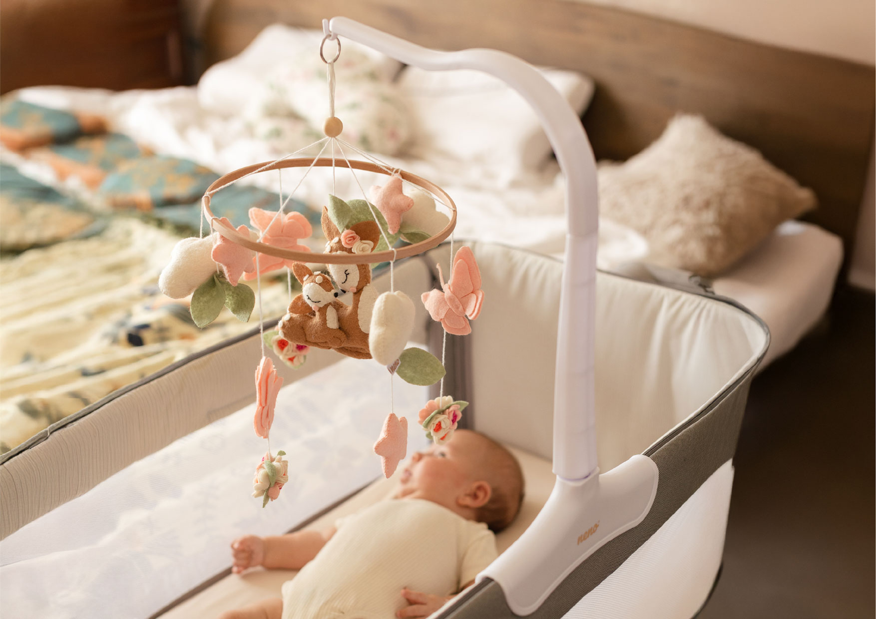 Karuzela Neno Rosi nad śpiącym niemowlęciem; motywy sarenek i motylków tworzą czarującą dekorację łóżeczka i kojącą atmosferę.